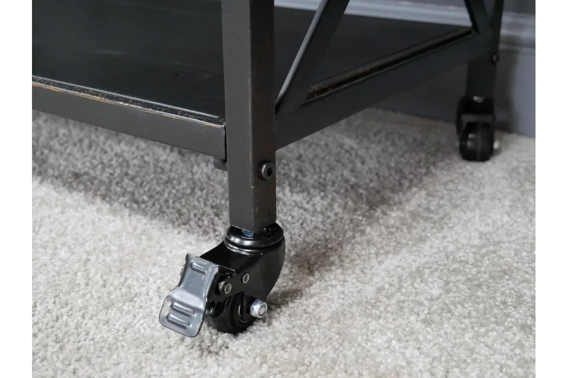 Close-up of black metal furniture leg with locking caster wheel on light carpet