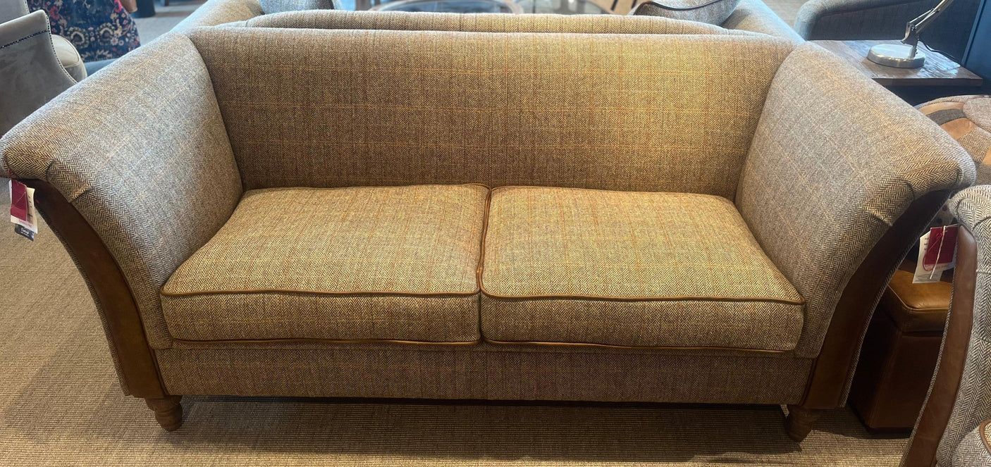 Fabric sofa with herringbone pattern, flared arms and wooden legs in showroom setting
