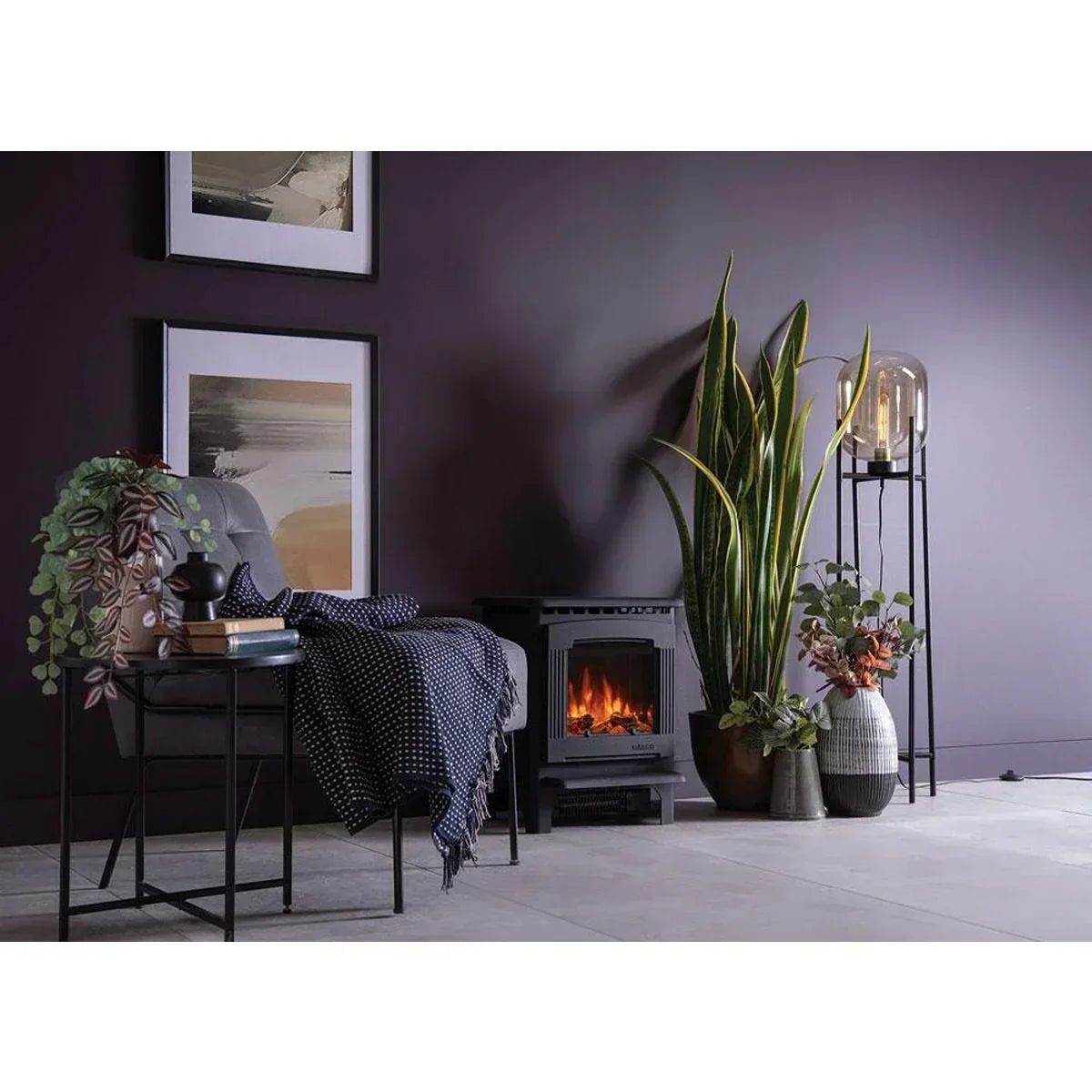 Modern living room with grey chair, electric fireplace, indoor plants and framed wall art