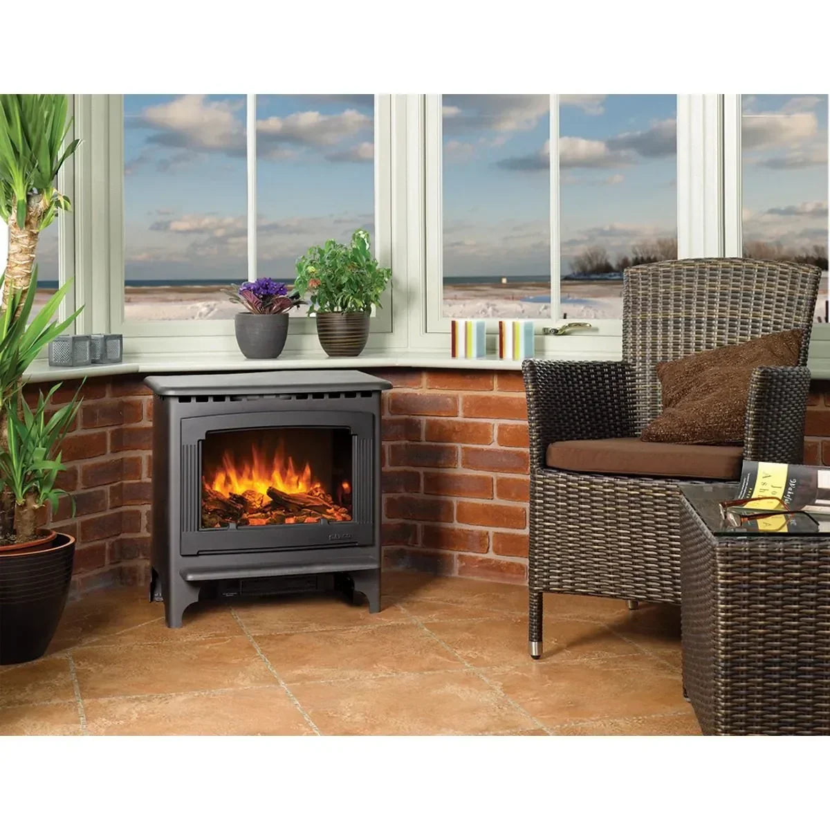 Electric stove heater with flame effect beside wicker chair in sunroom with brick wall