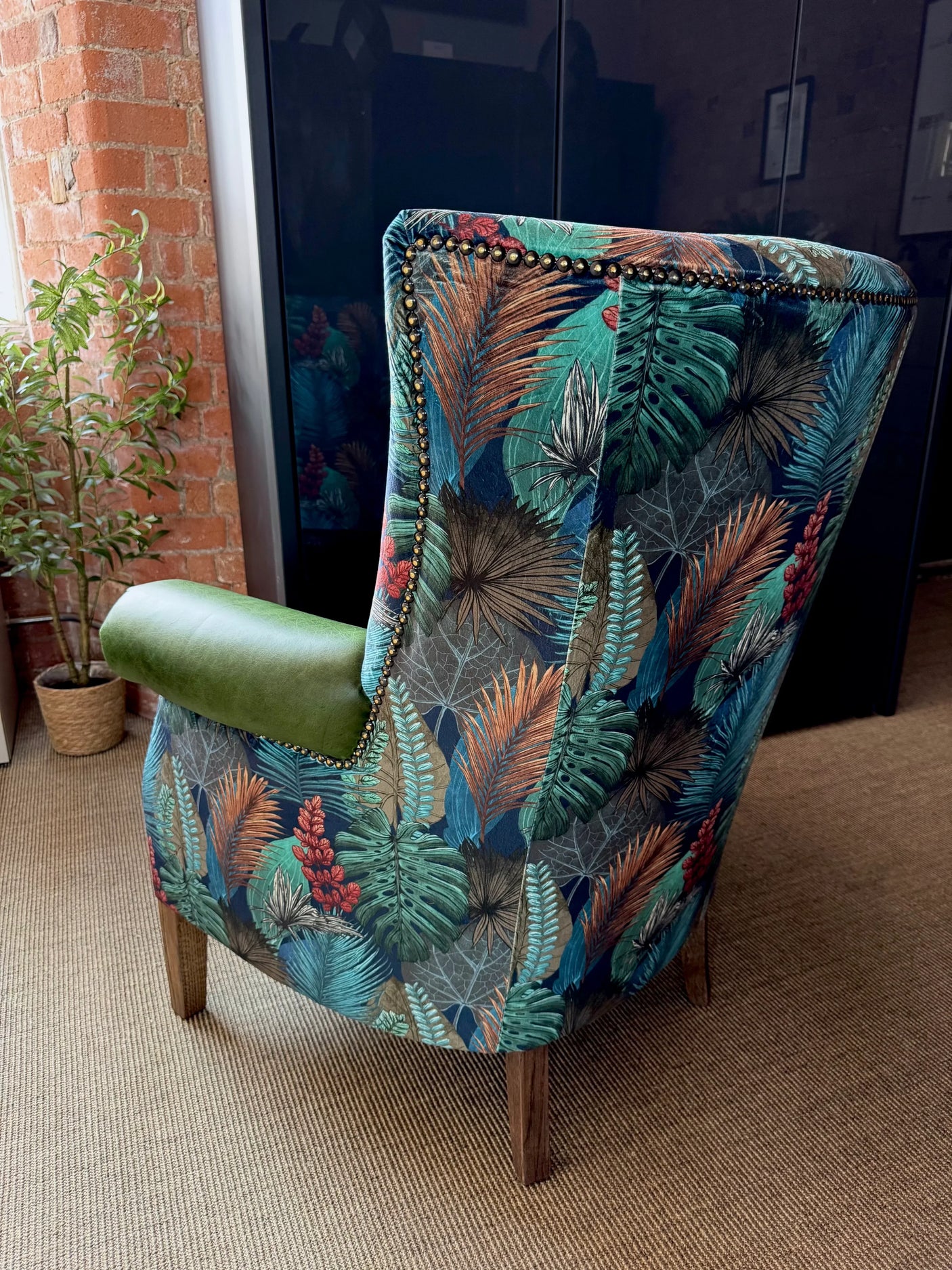 Patterned accent armchair with leaf print upholstery and wooden legs in living room setting