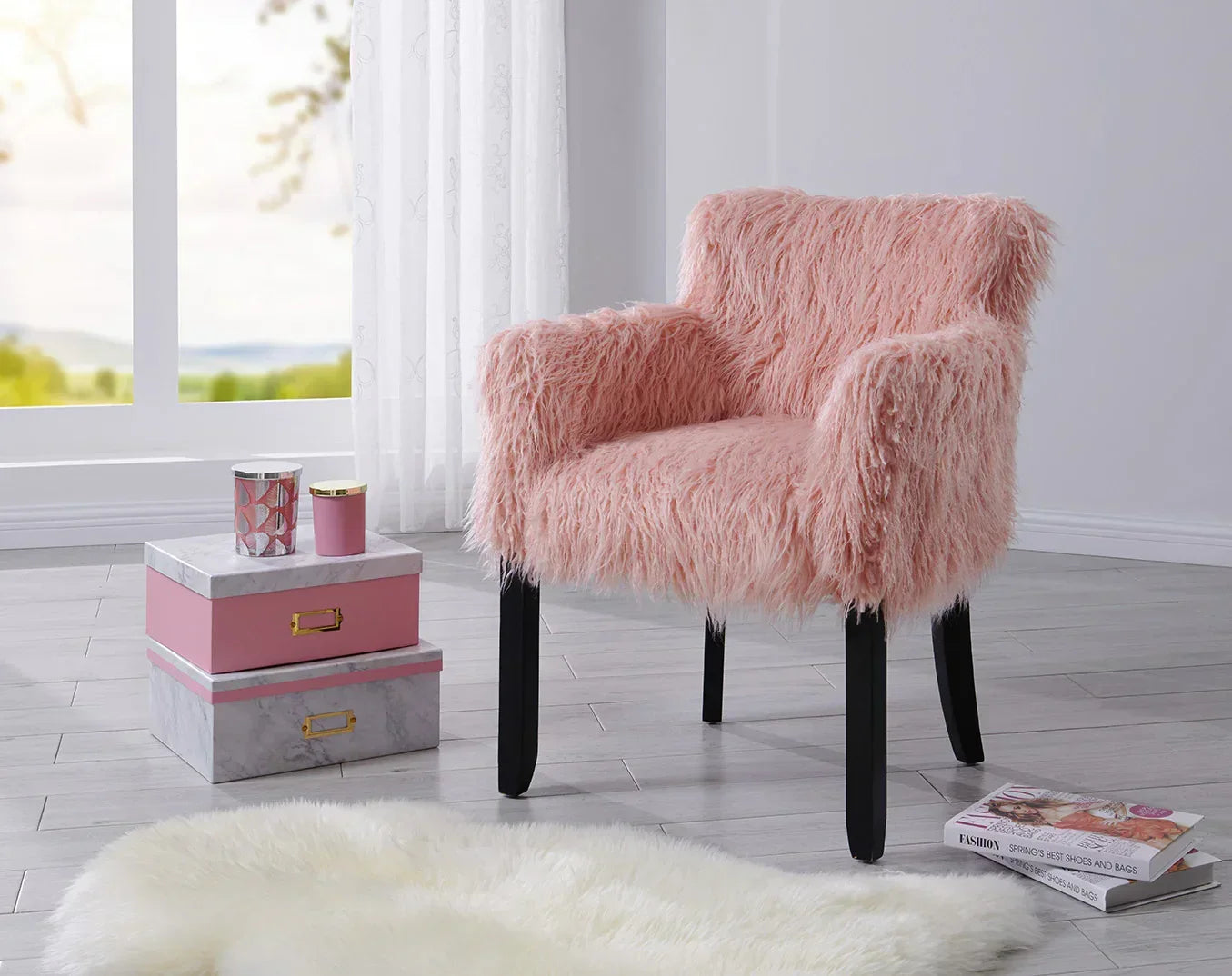 Pink faux fur accent chair with black legs in a modern living room next to decorative boxes
