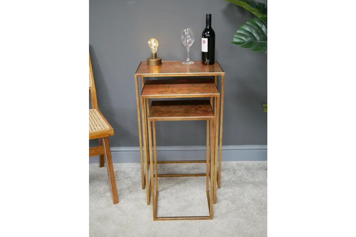 Gold metal and wood nesting tables set with lamp, wine bottle, and glass in living space