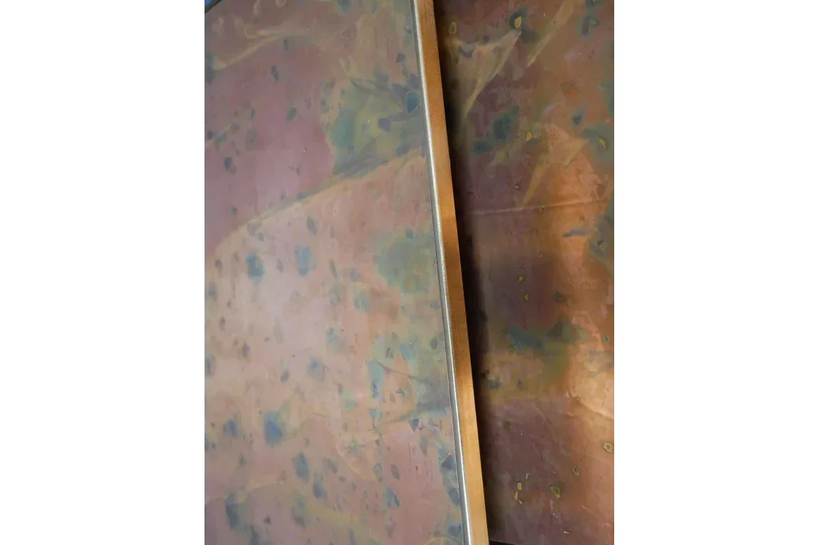 Closeup of metal table top with multicolored patina finish and straight edge detail