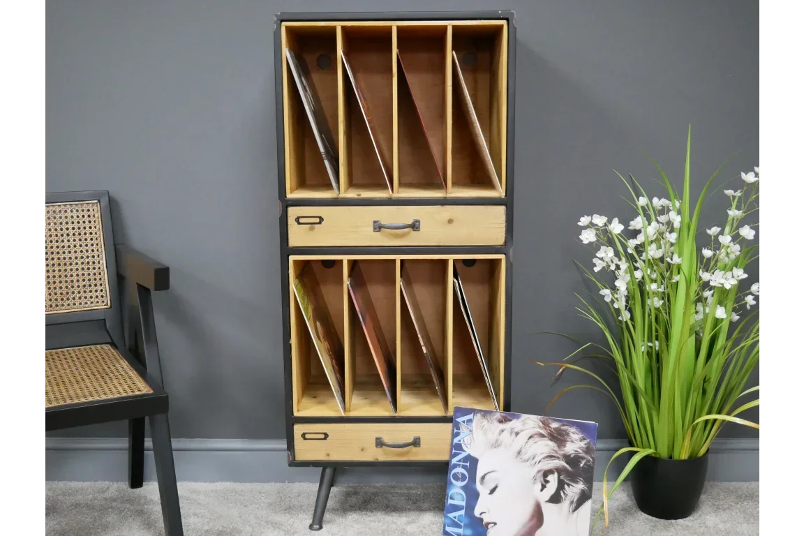 Wooden vinyl record storage cabinet with dividers and drawers next to chair and plant