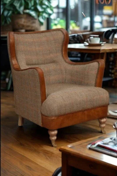 Brown fabric armchair with leather trim and wooden legs in a living room setting