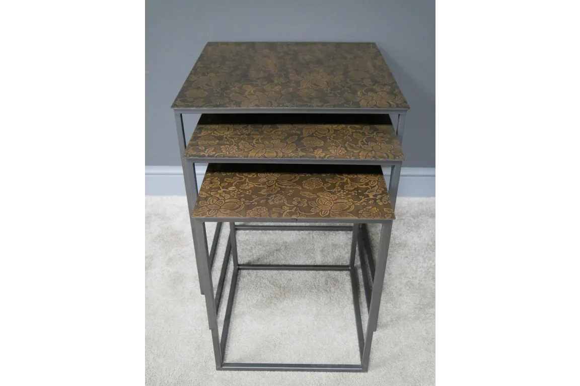 Set of three nesting tables with floral patterned tops and metal frames on carpet