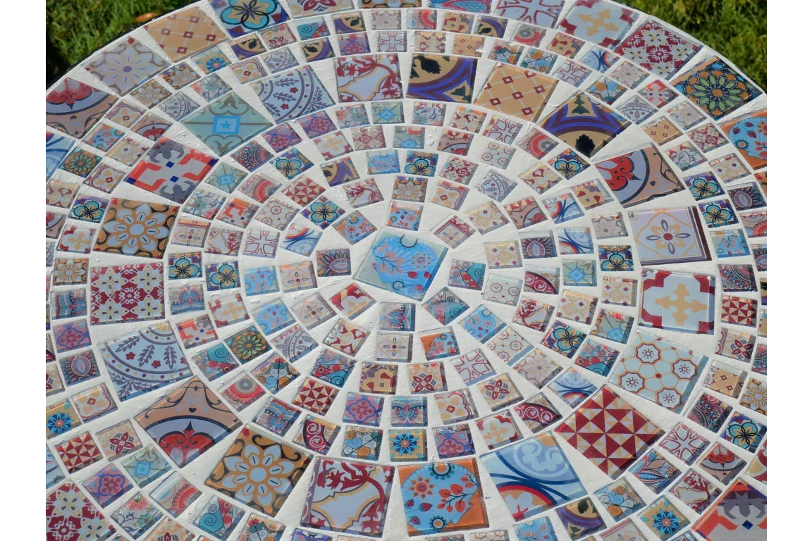 Round mosaic garden table top with multicolored patterned ceramic tiles closeup