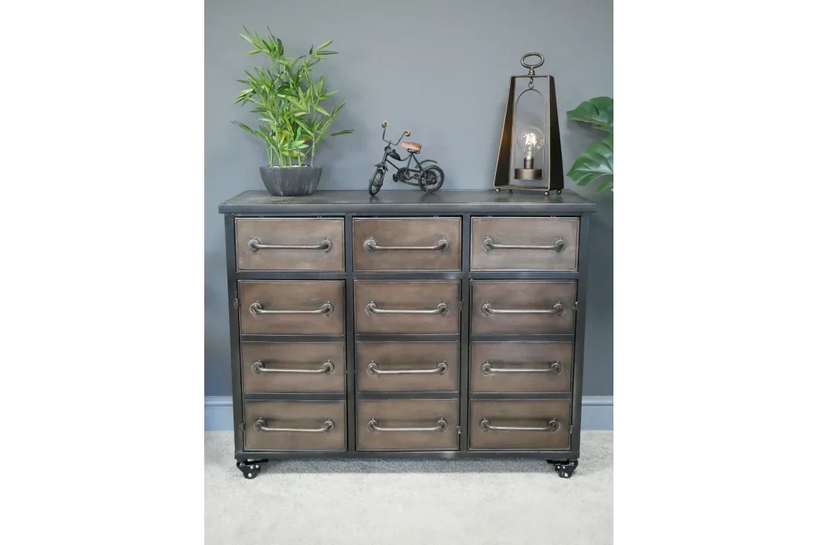 Industrial metal chest of drawers with large handles, styled with lamp, plant, and decor accents