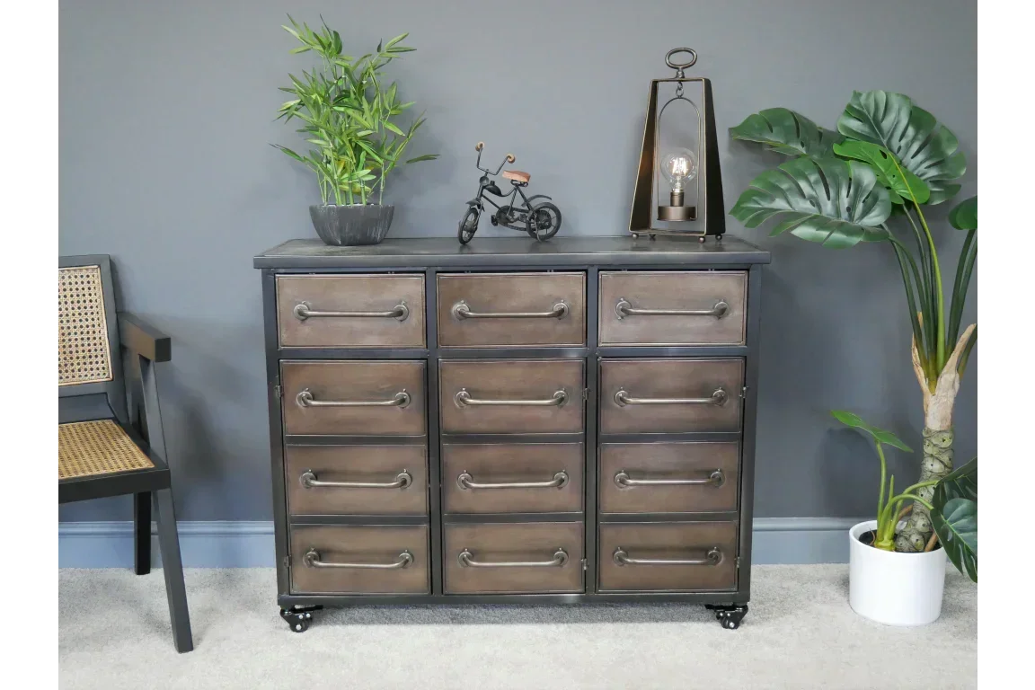 Industrial style metal chest of drawers with metal handles, decor and plants beside grey wall