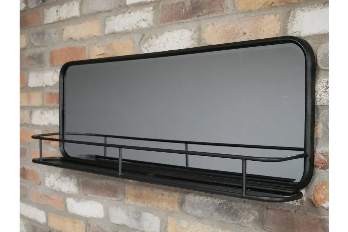 Black metal wall shelf with rail and rectangular mirror on brick wall