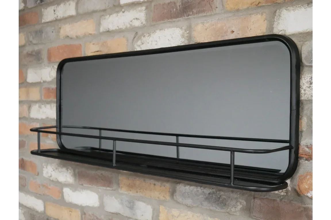 Rectangular wall mirror with black metal frame and shelf mounted on brick wall