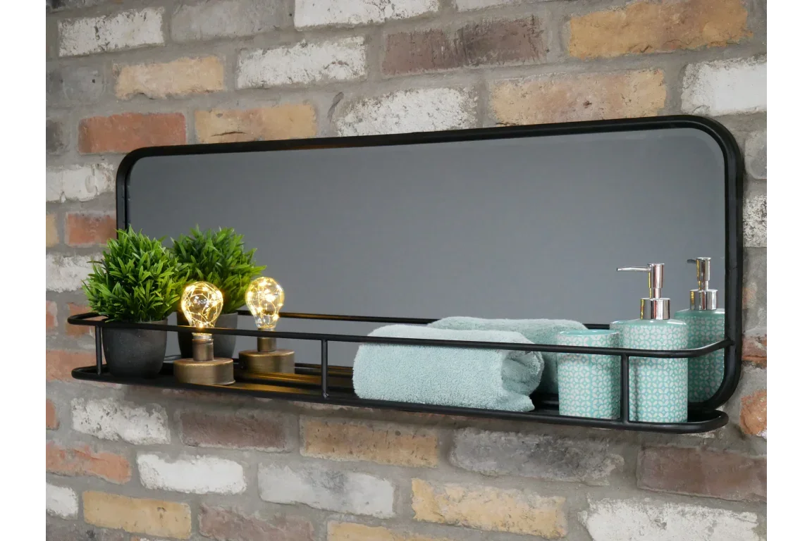 Black metal framed wall mirror with shelf, holding towels, soap dispensers, plants, and lights