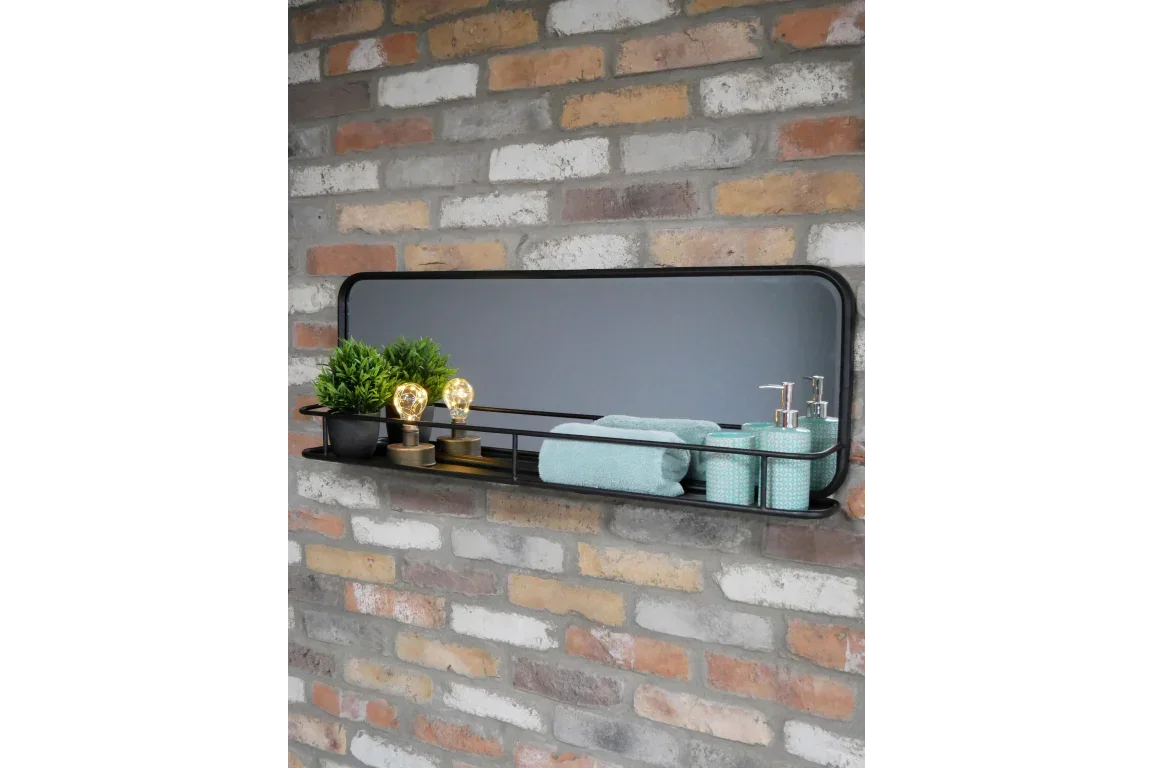 Rectangular wall mirror with black shelf holding plants, towels, and teal bathroom accessories