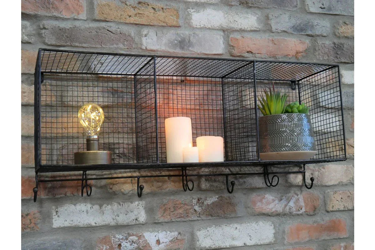 Industrial wire wall shelf with LED bulb, candles, and small plant pot on brick wall