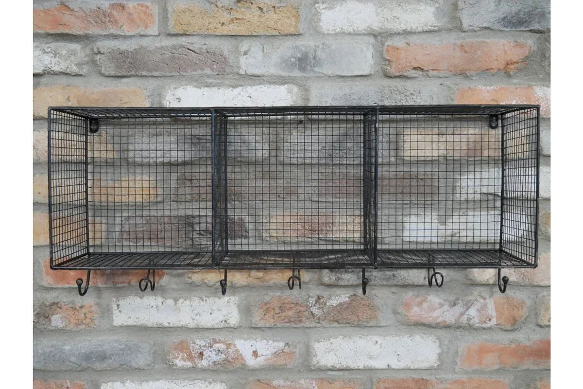 Black wire wall shelf with three cubbies and hooks mounted on exposed brick wall