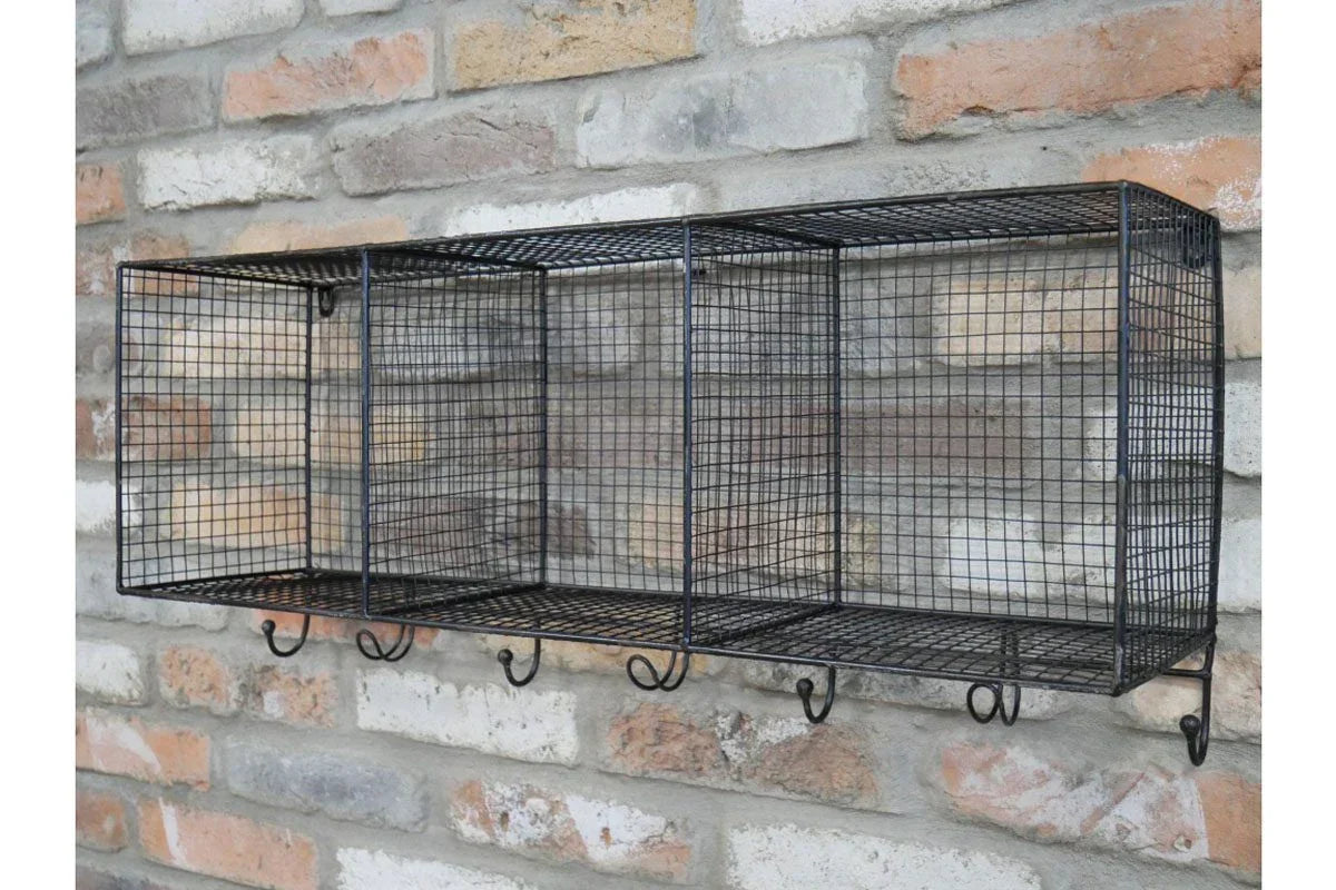 Black wire wall storage rack with compartments and hooks mounted on brick wall