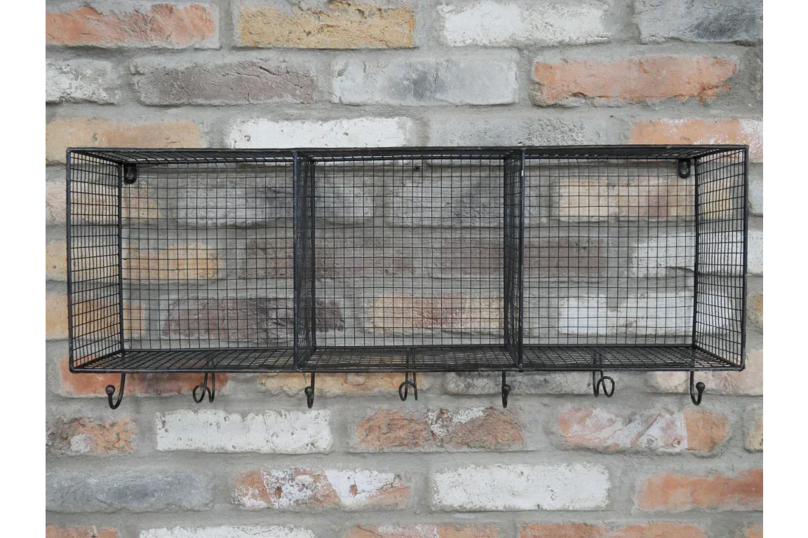 Black wire mesh wall shelf with three compartments and hooks mounted on brick wall