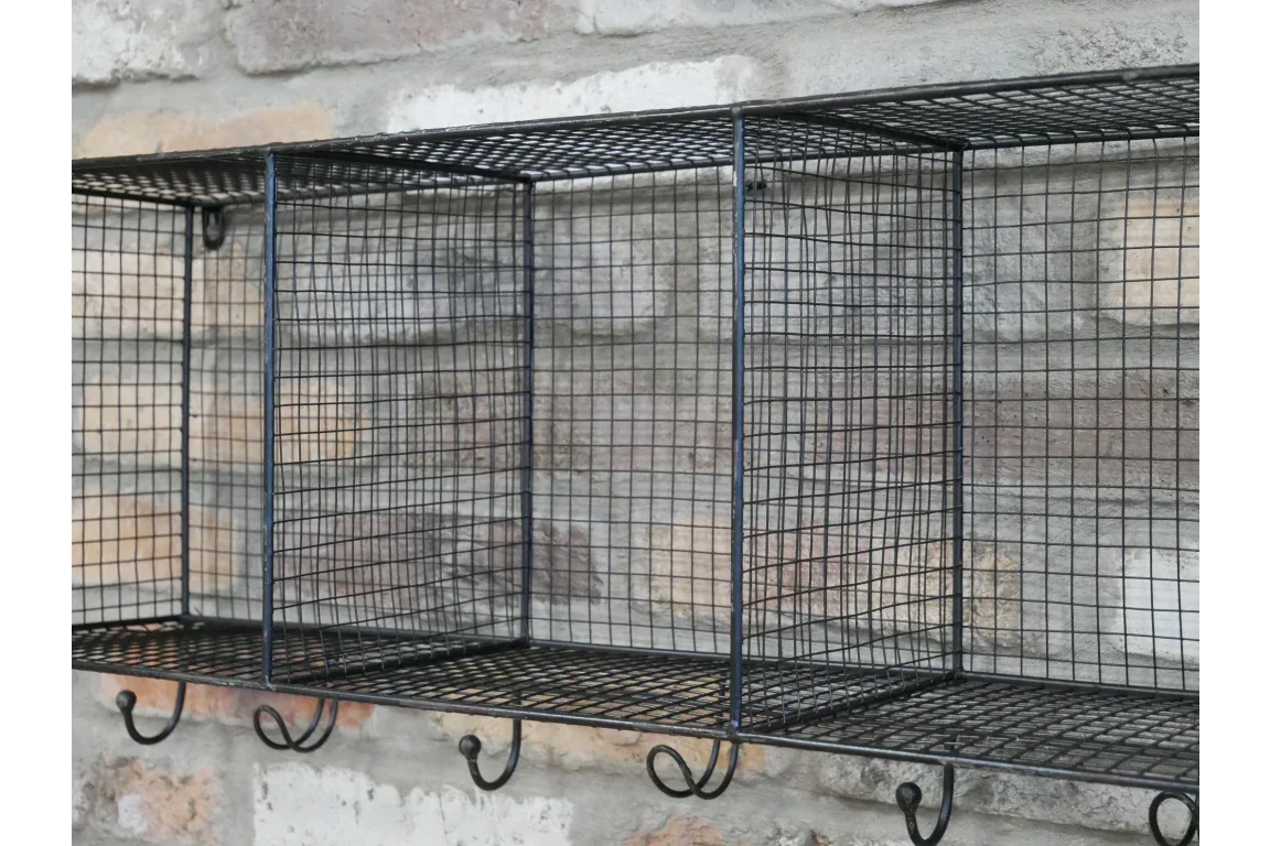 Black metal wire storage shelf with hooks mounted on exposed brick wall