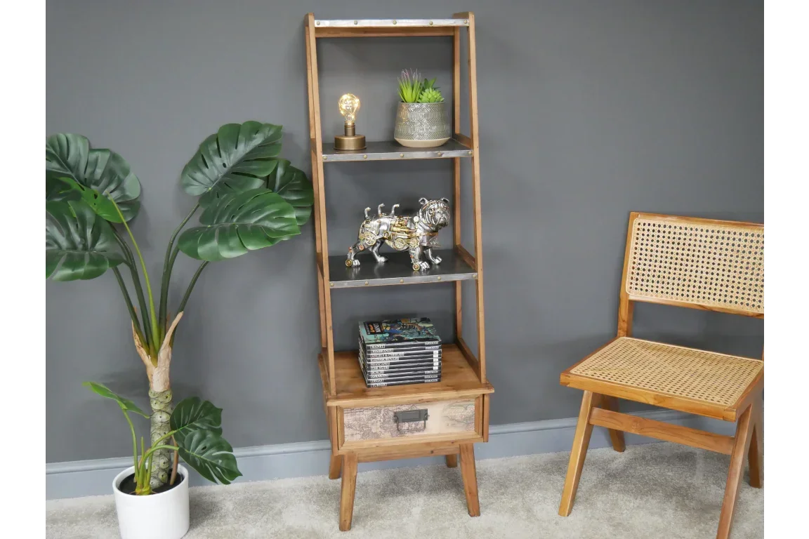 Wooden shelving unit with decorative drawer beside rattan chair and potted plant