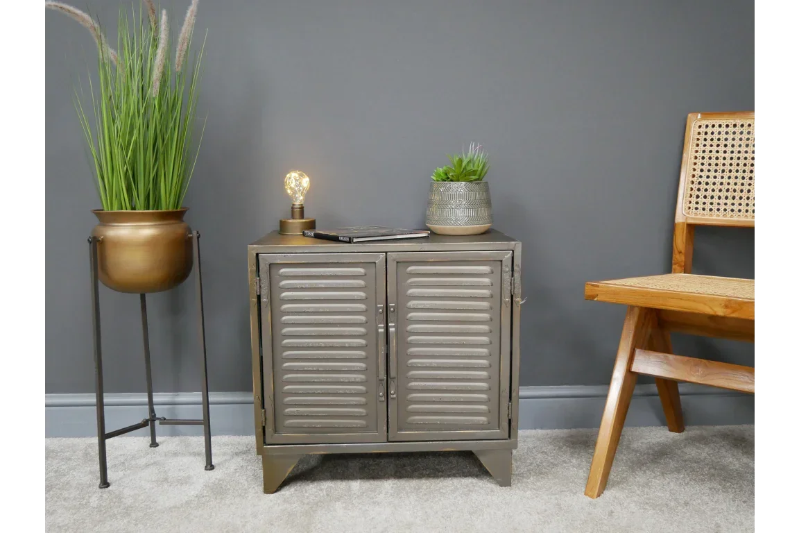 Metal storage cabinet with louvered doors beside indoor plant and wooden chair
