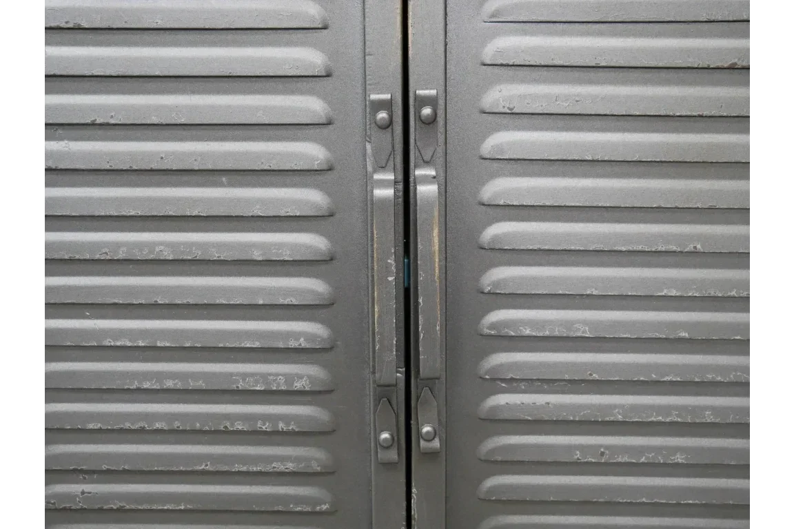 Close view of grey metal cabinet doors with vertical handles and horizontal grooves