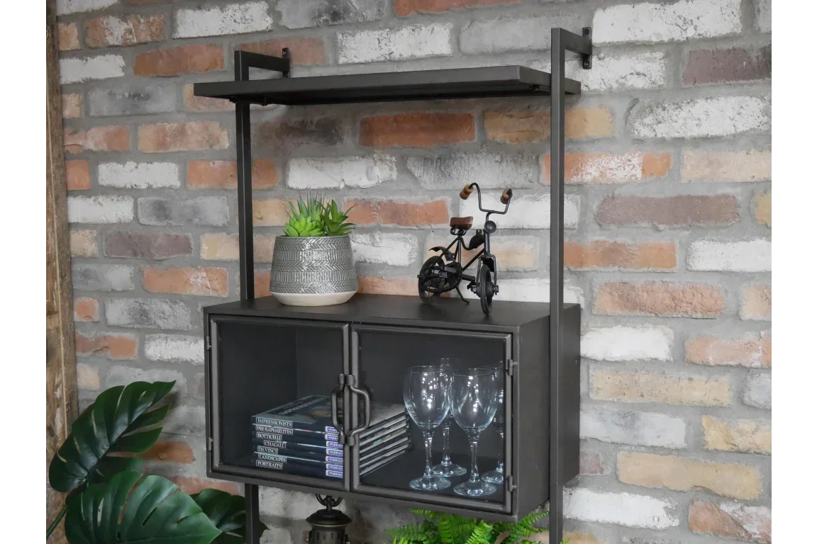 Industrial wall cabinet with glass doors holding books and wine glasses, brick wall backdrop