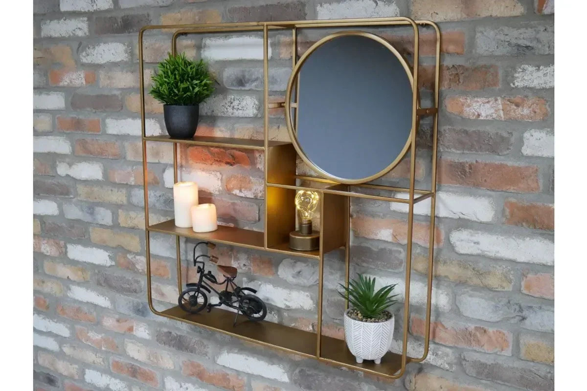 Gold metal wall shelf with round mirror, candles, decor plants and ornaments on brick wall