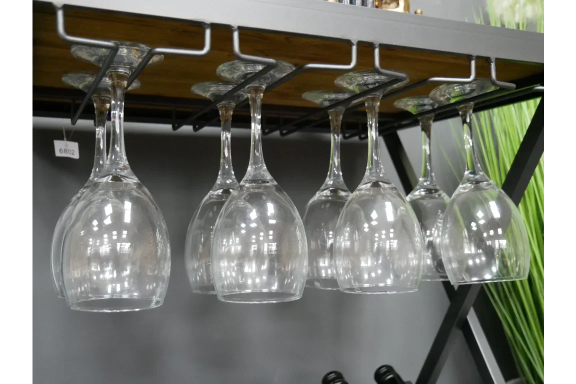 Set of wine glasses hanging upside down on metal rack under wooden shelf