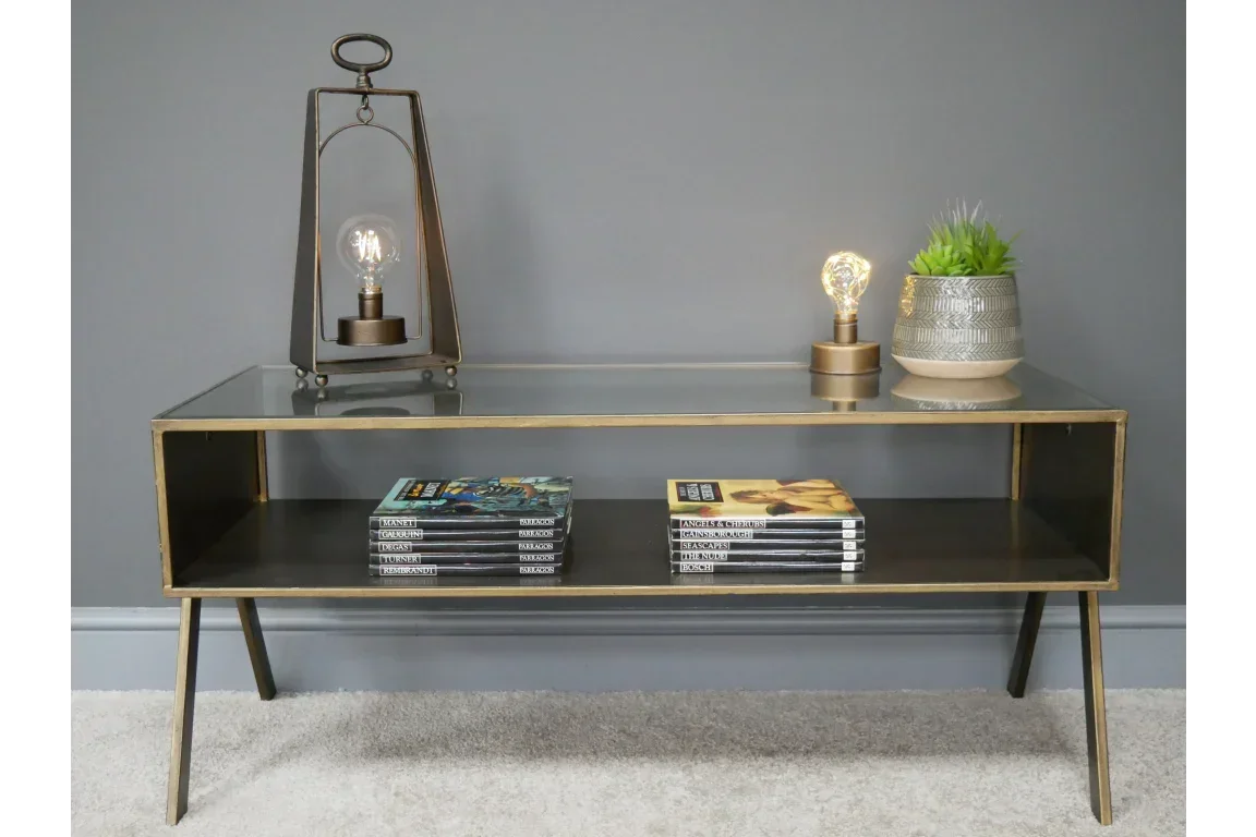 Glass top console table with gold frame, books, modern lamp and potted plant decor
