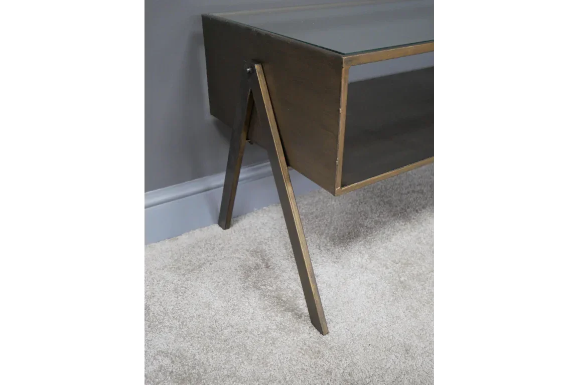 Wooden console table with angled legs and open shelf against grey wall on carpet