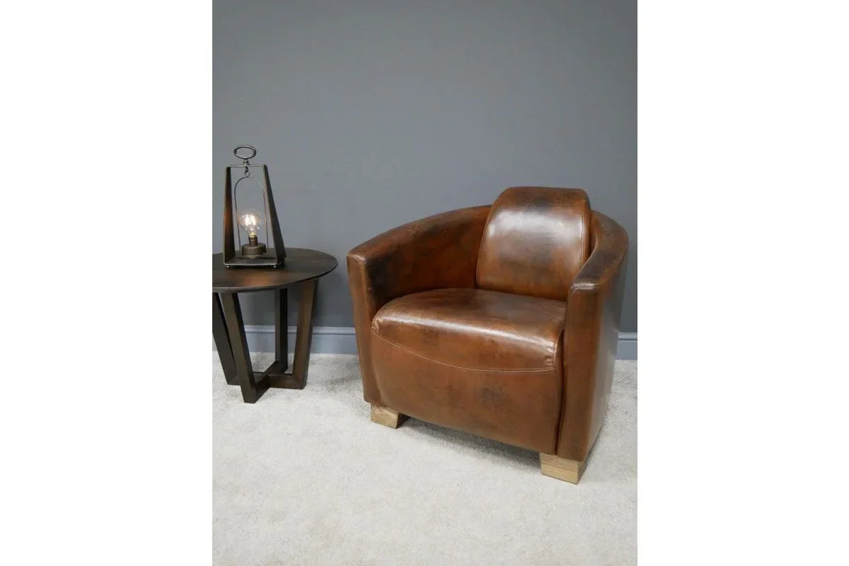 Brown leather armchair with rounded back beside dark wooden side table and lamp