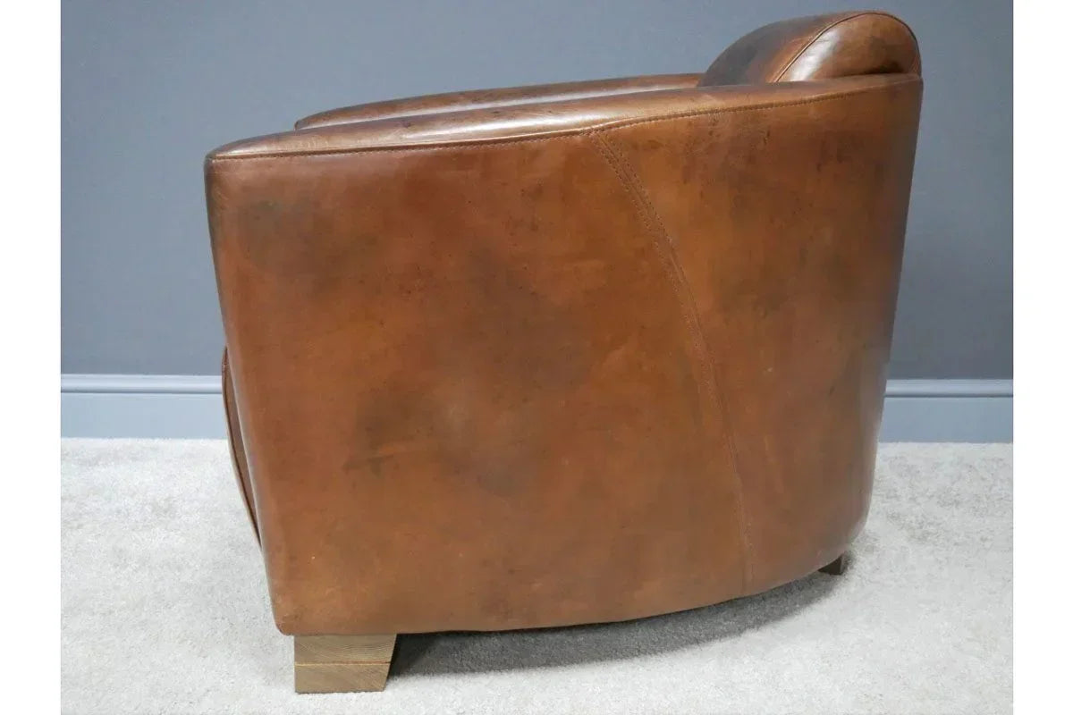 Brown leather armchair side view with wooden legs on light carpet