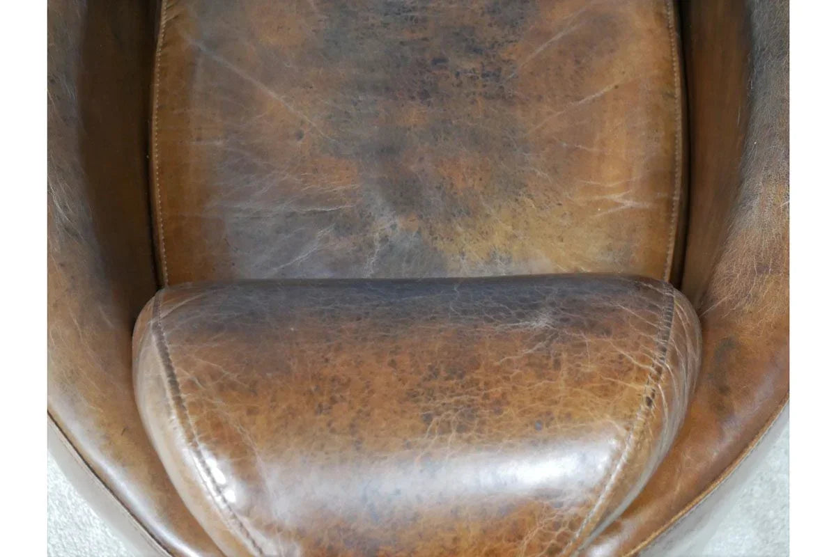 Distressed brown leather armchair seat close-up showing texture and stitching detail