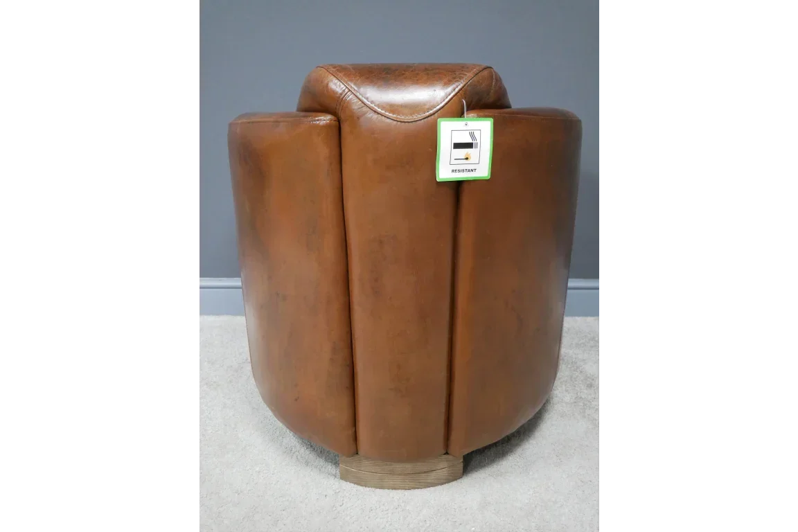 Brown leather armchair rear view on grey carpet, visible fire resistant label on back