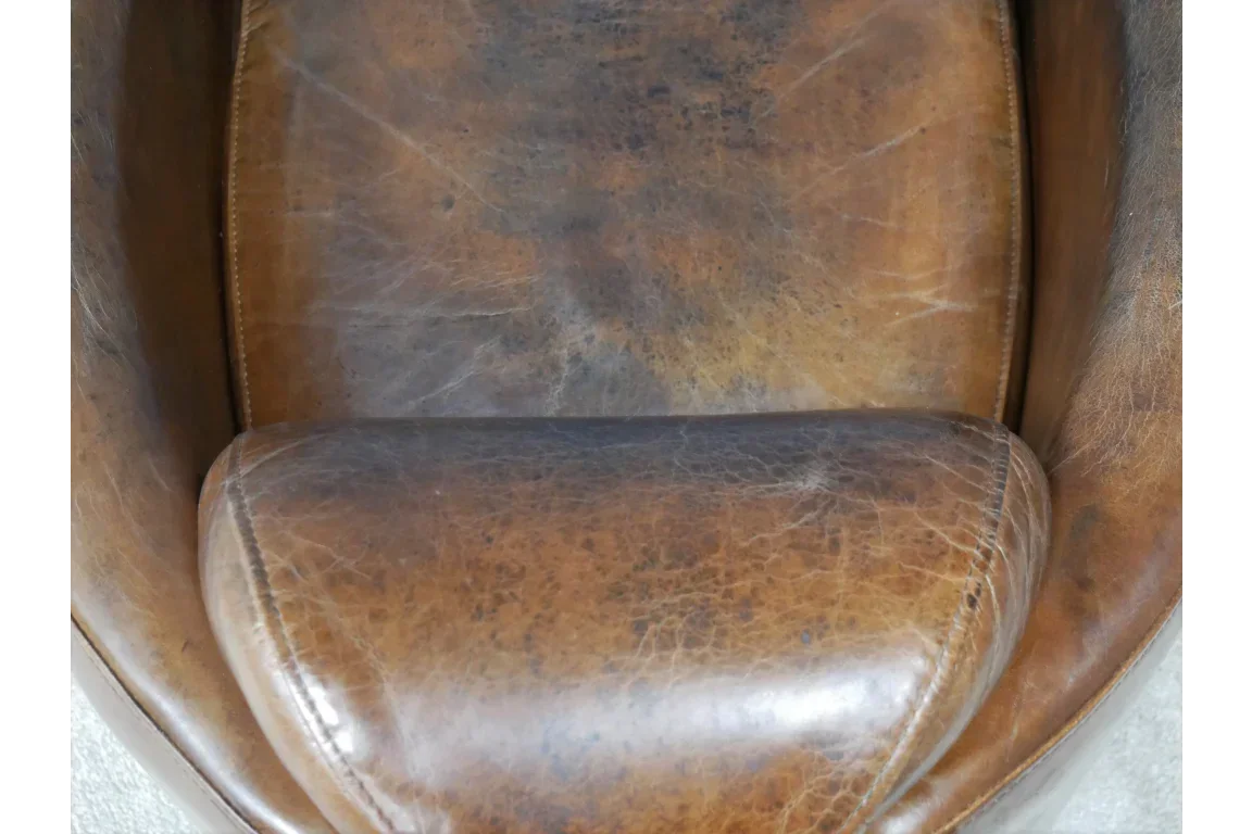 Close-up brown leather armchair seat with visible aged texture and stitching detail