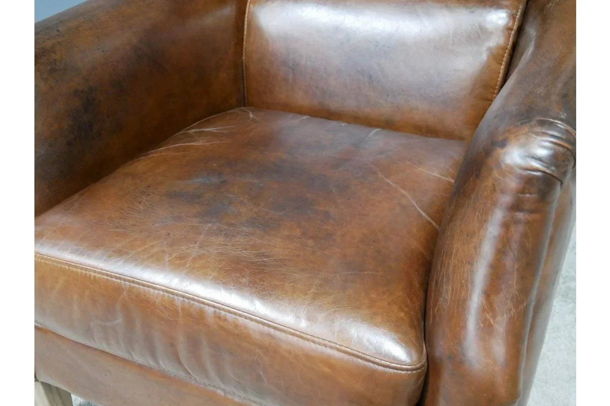 Distressed brown leather armchair seat with visible grain and stitching detail