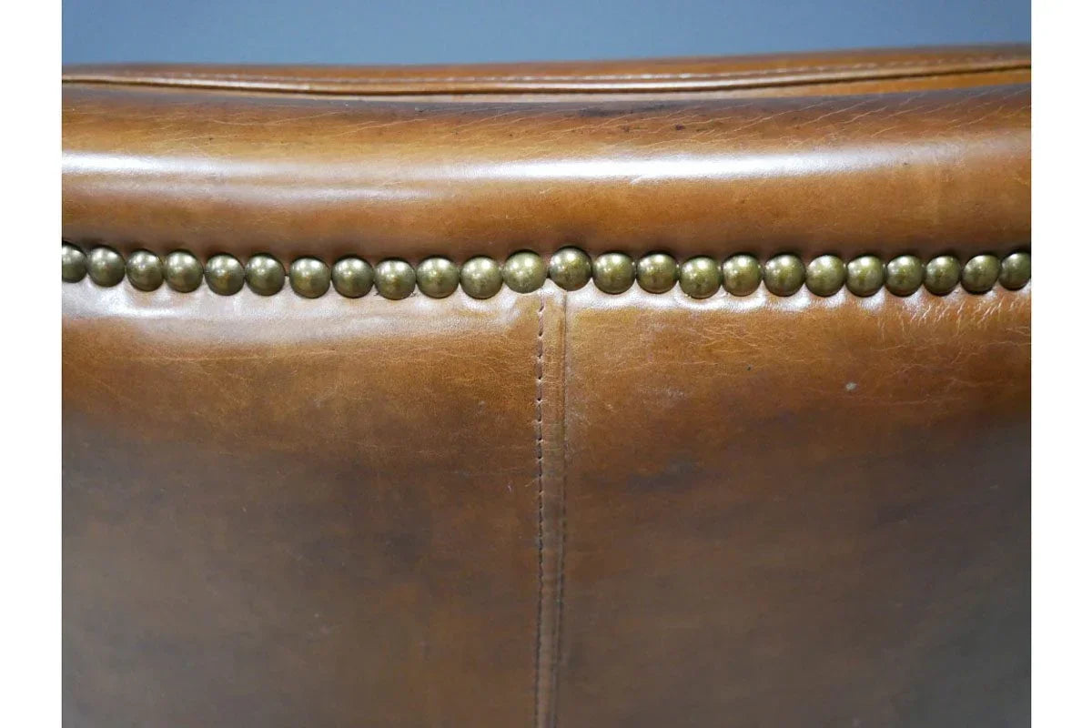 Tan leather chair back with brass stud detailing and visible seam stitching