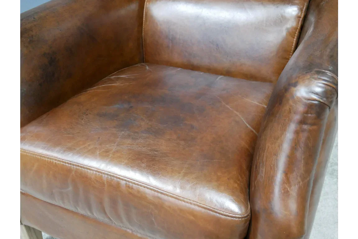 Brown leather armchair seat with visible aged patina and cushioned armrests