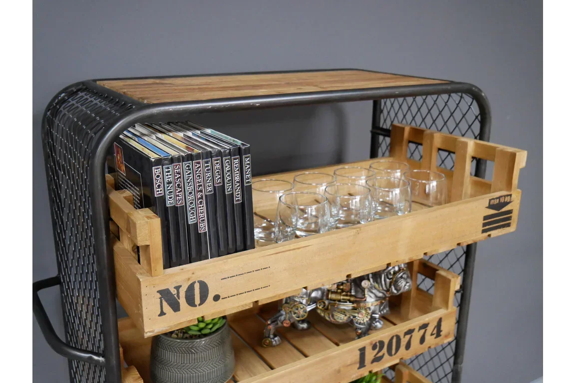 Industrial style wooden and metal storage cart with shelf holding books and glass tumblers