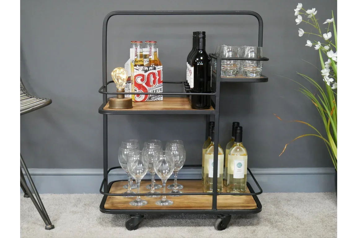 Industrial bar cart with wooden shelves, wine bottles, glasses, and drinks against grey wall