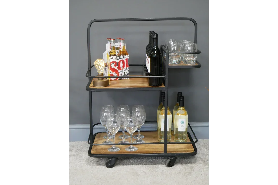 Industrial style drinks trolley with black metal frame, wooden shelves, glasses and bottles