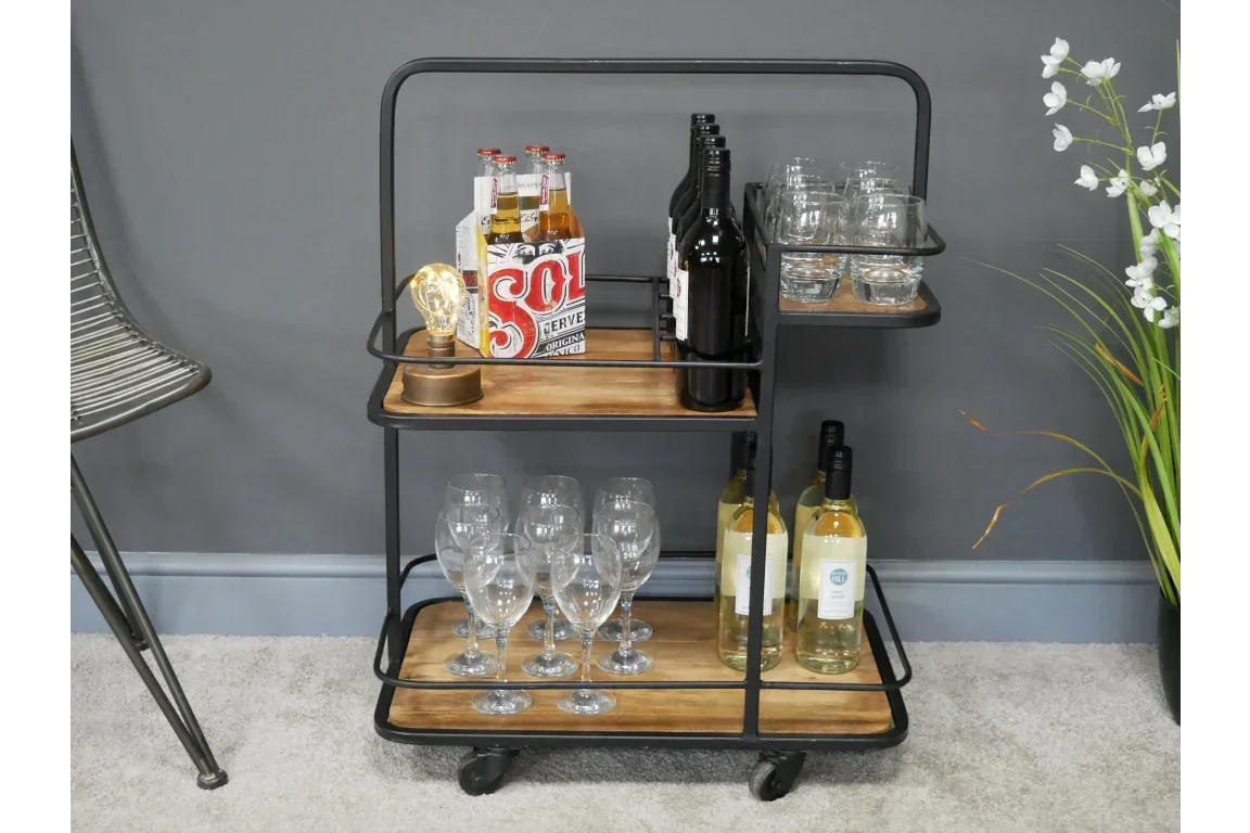 Industrial style drinks trolley with wood shelves, glassware, and bottles on casters