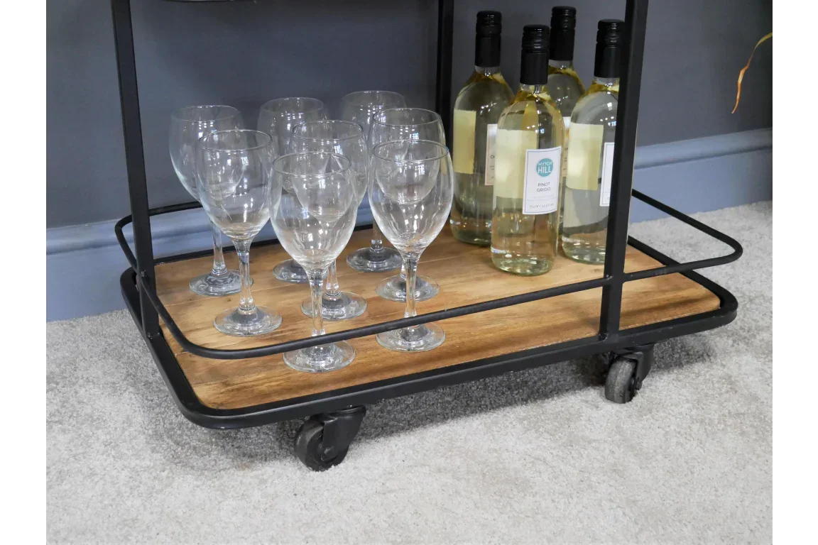 Bar cart lower shelf with wine glasses and bottles on wood tray