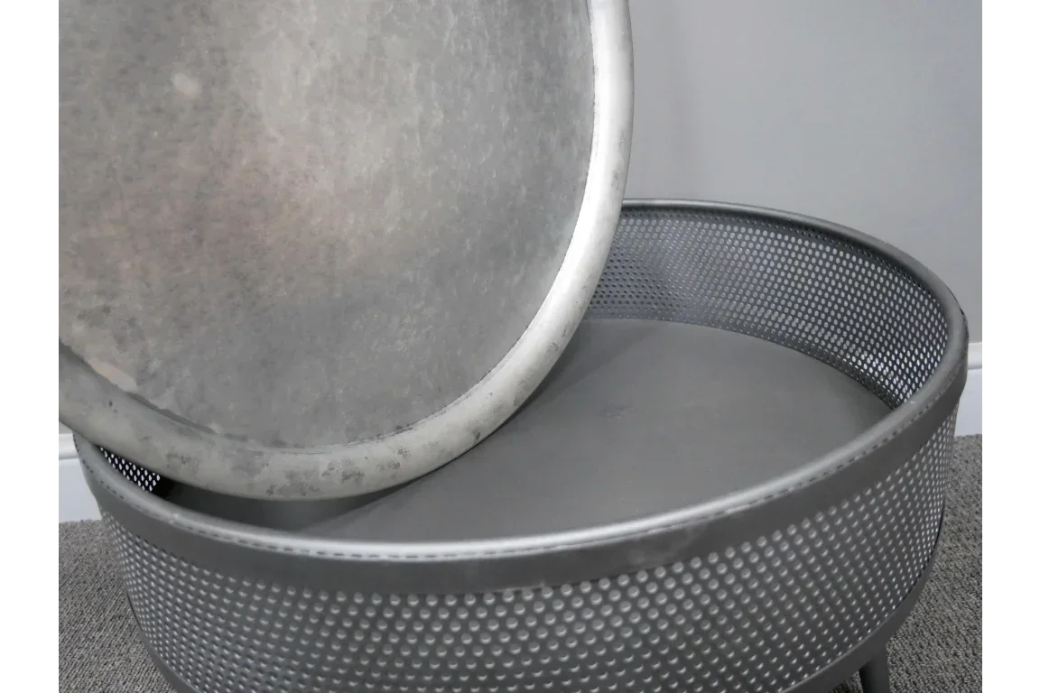 Round metal storage table with removable perforated lid in grey finish on carpeted floor