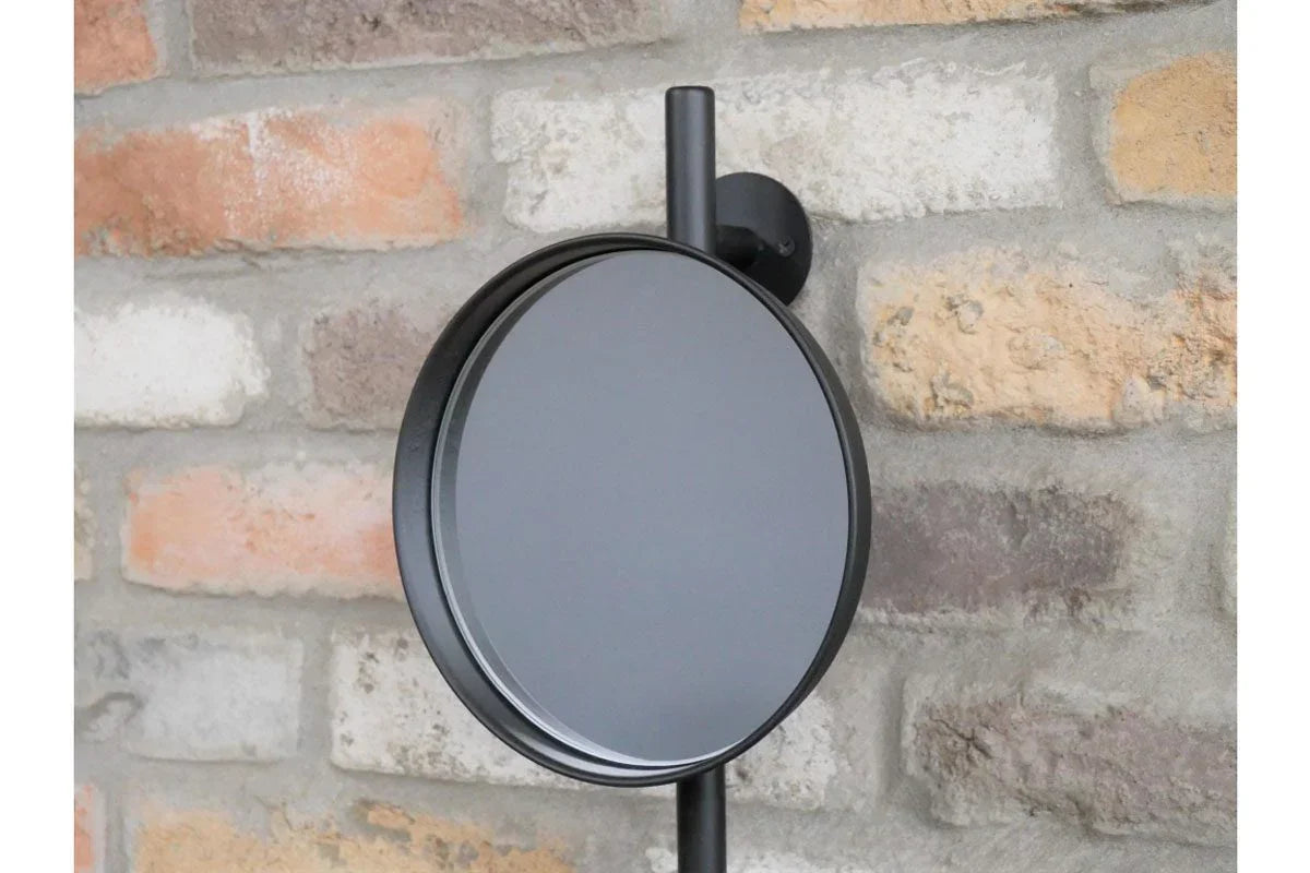 Round black wall mirror with metal frame mounted on exposed brick wall