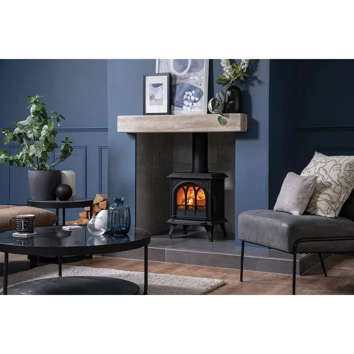 Black wood burning stove in modern living room with grey armchair and blue decor accents