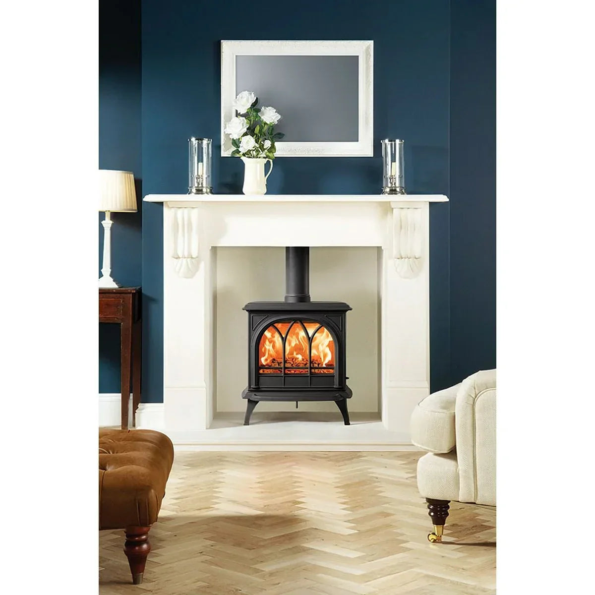 Black wood burning stove with glass door set in white fireplace, herringbone floor