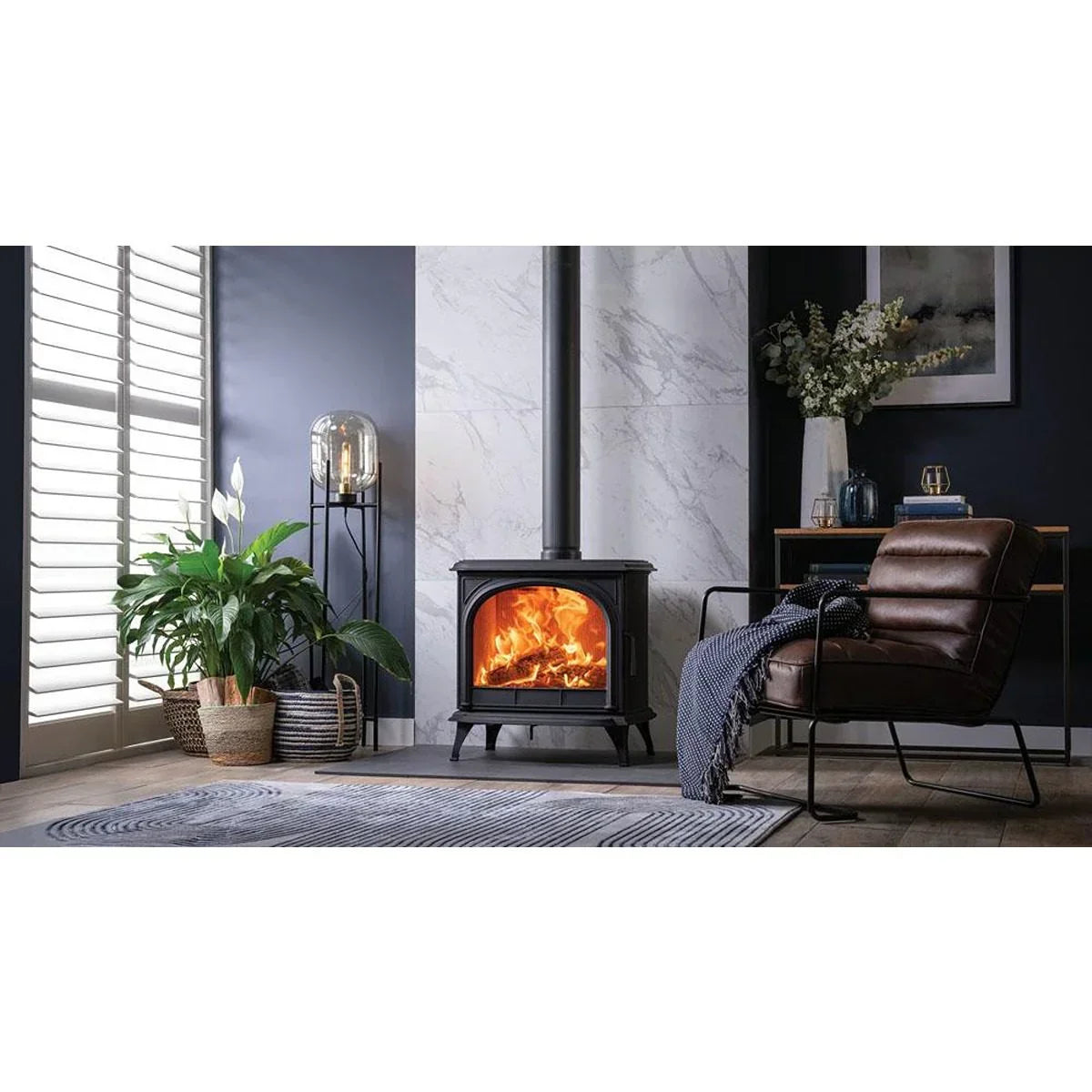 Black wood burning stove in modern living room with leather armchair and indoor plants