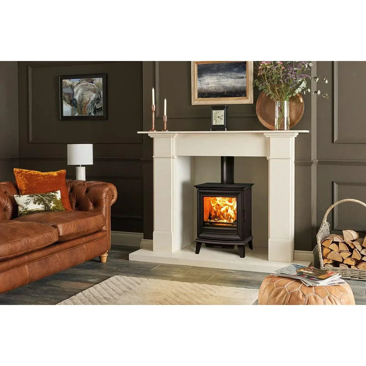 Living room with leather sofa, wood burning stove fireplace, and stacked firewood